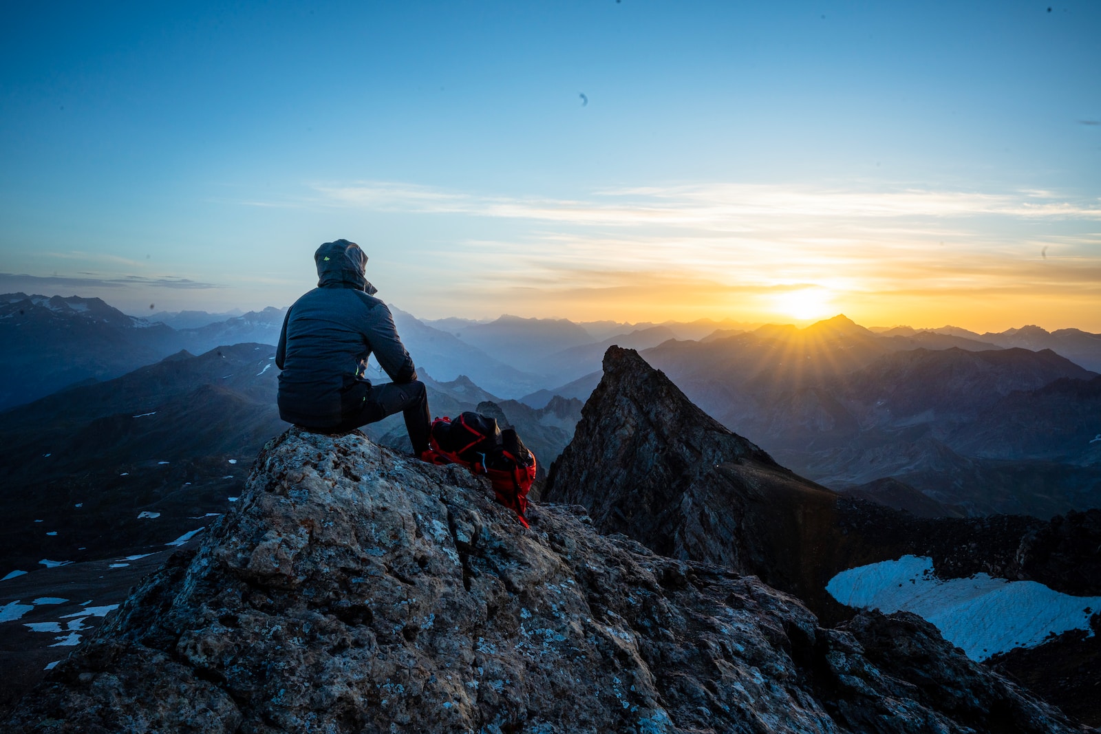 man in black jacket sitting on rock during daytime